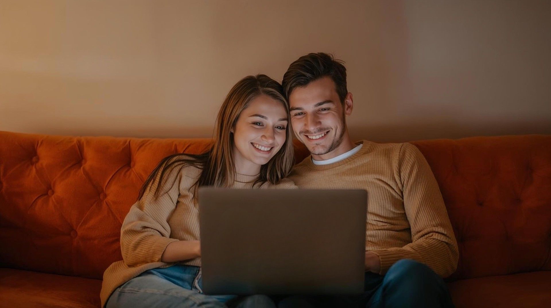 a young couple smiling while looking at a laptop screen
